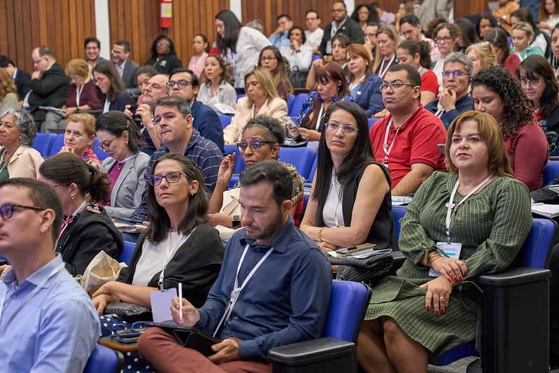 Audience members seated in an auditorium, attentively listening to a session during the AMR regional meeting in Brasília.