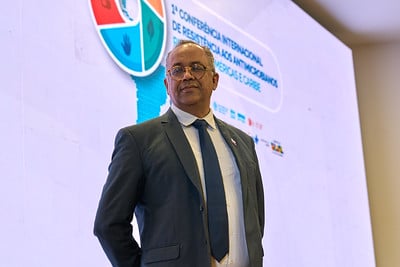André Abreu standing on stage in front of a presentation screen during the AMR conference in Brasília, with event branding visible in the background.